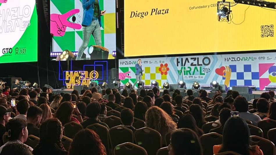 Diego Plaza presentado en pantalla gigante ante un auditorio lleno.
