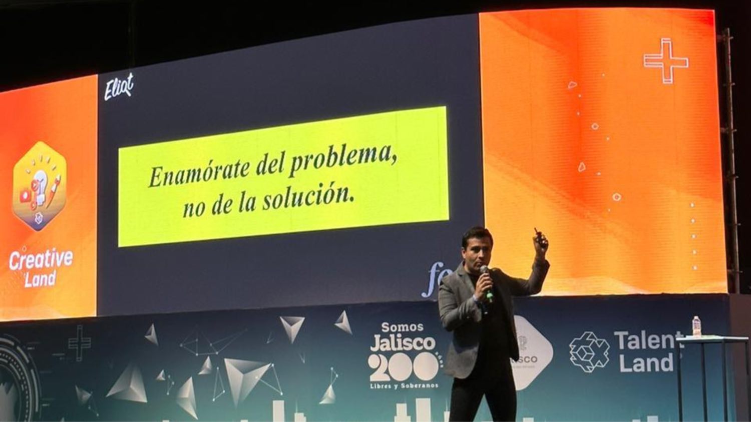 Diego Plaza con micrófono en Talent Land, junto a la frase «Enamórate del problema, no de la solución».