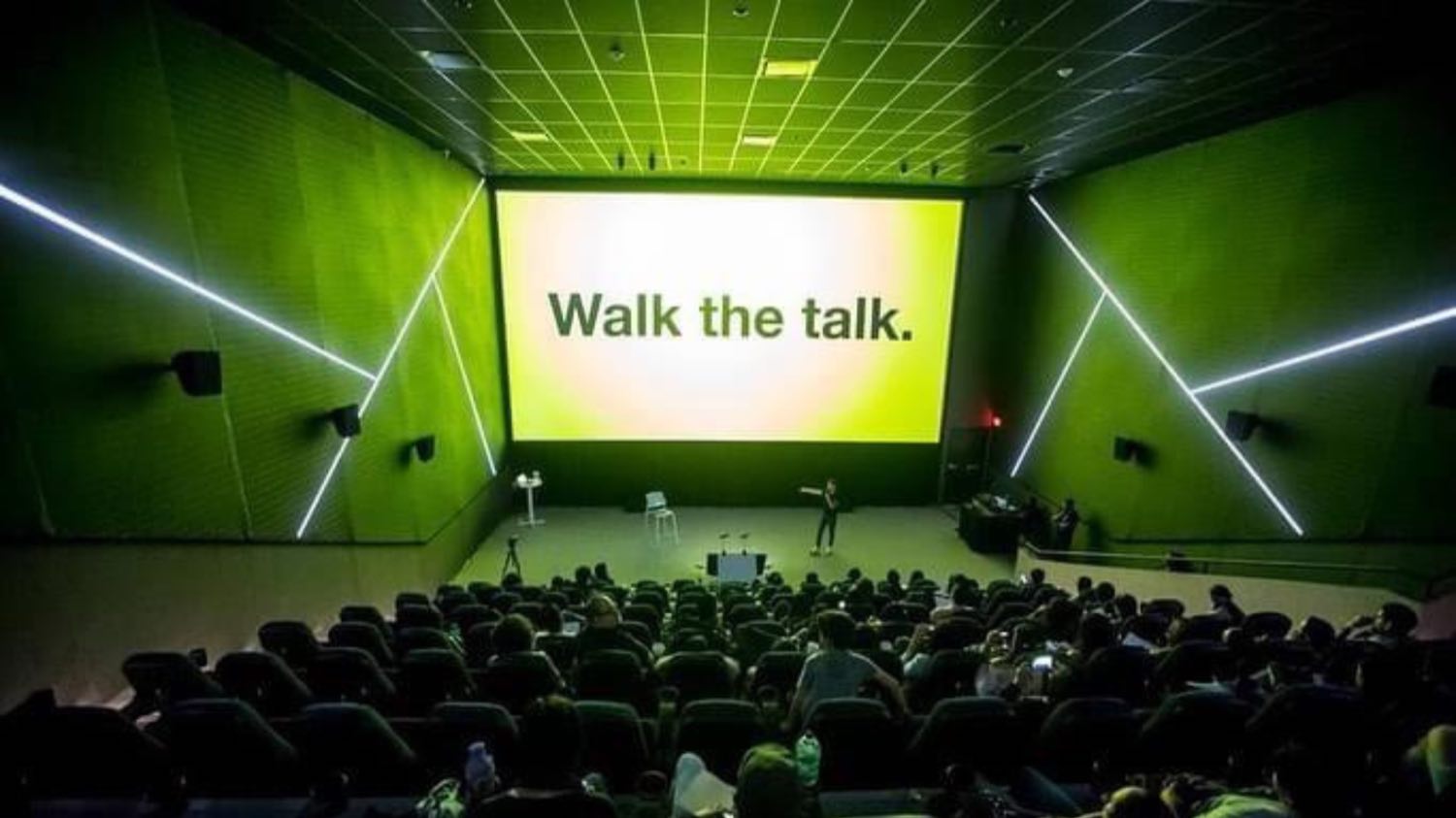 Auditorio verde con la pantalla «Walk the talk».