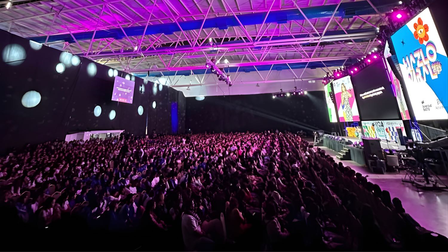 Auditorio multitudinario con iluminación morada.